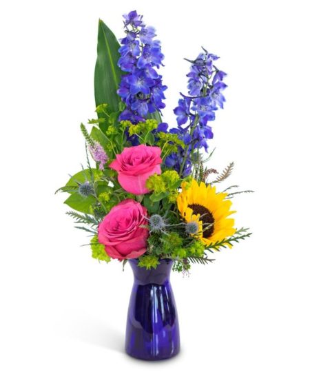 Feel the weekend vibes with a flower arrangement chock-full of fun, energy, and elegance! Weekend Vibe features blue delphinium, adorable and energetic pink roses, a sassy sunflower, all surrounded by lushes foliage in a cobalt blue glass vase.