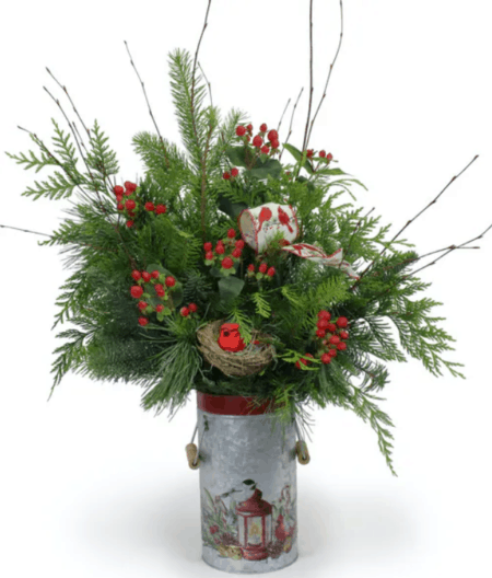 small cardinal perched in the bouquet on a nest. Loops of coordinating cardinal ribbon are included along with red hypericum berries. The arrangement is a taller design and is perfect for a kitchen island or even a breakfast table. The keepsake galvanized tin pail with wooden handles has a rustic print of a red lantern with a bird perched on top. 
