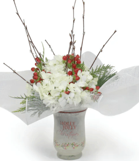 Fluffy white Hydrangeas, a southern favorite, with bright red hypericum berries are a perfect for the season. Natural birch adds a touch of nature along with fragrant evergreens. Created in a keepsake frosted glass vase with iridescent white mesh collar. 