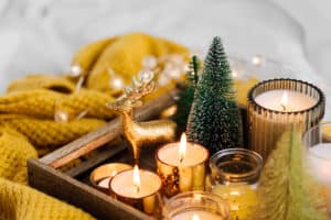 Burning candles and christmas decorations on wooden tray with warm plaid. Winter cozy style. Hygge concept.
